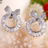 Pair of diamond earrings with bow design on a textured surface