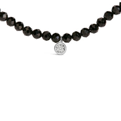Necklace with black beads and a silver pendant on a white background