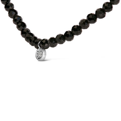 Black beaded necklace with a silver pendant on a white background