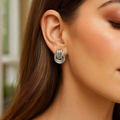 Close-up of a woman wearing a silver knot earring with a blurred background