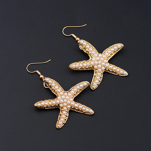 Starfish-shaped earrings with pearl details on a black background