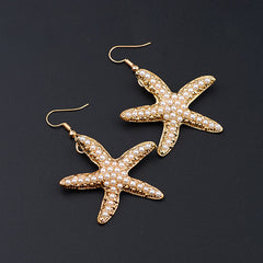 Starfish-shaped earrings with pearl details on a black background