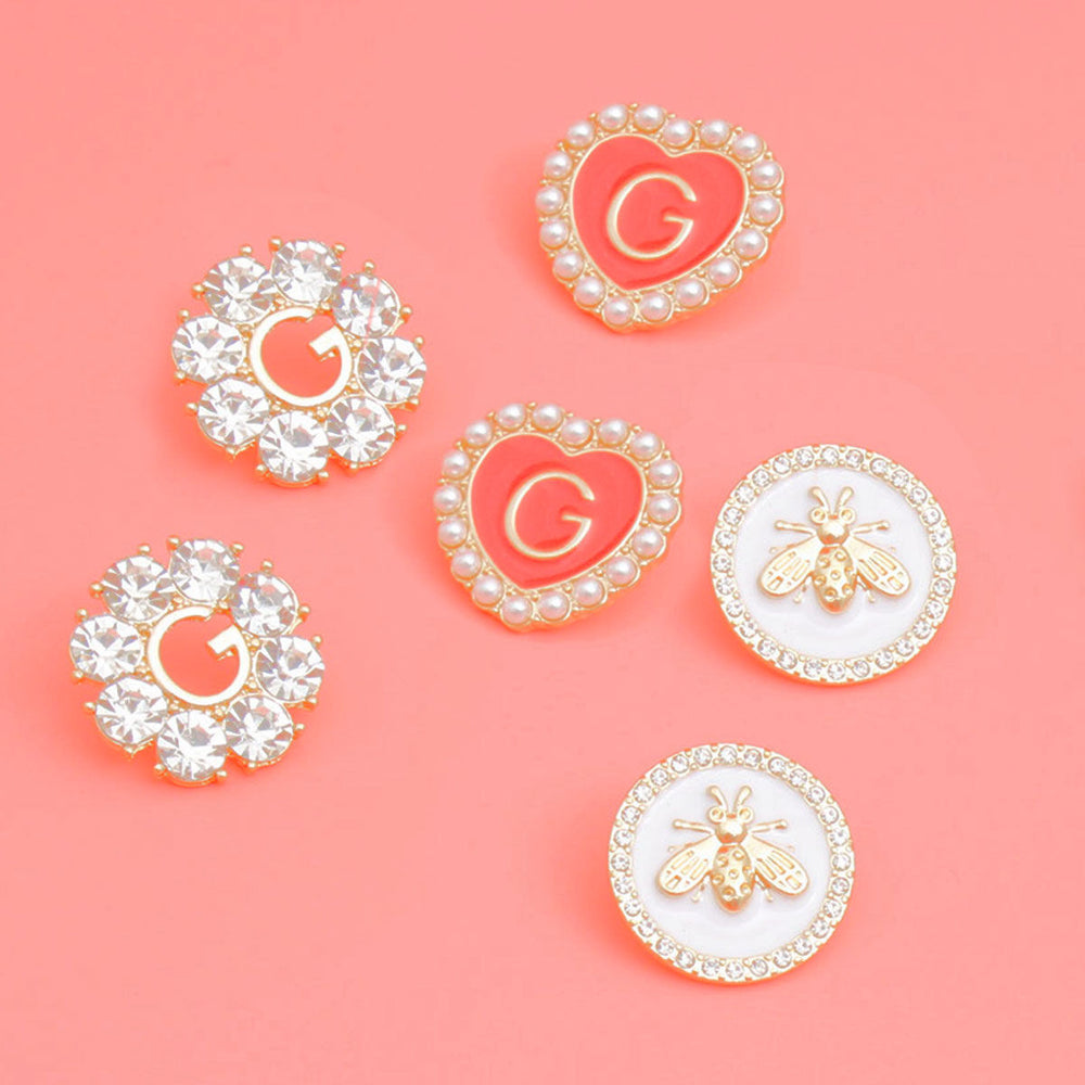 Set of decorative pins with 'G' and bee designs on a pink background