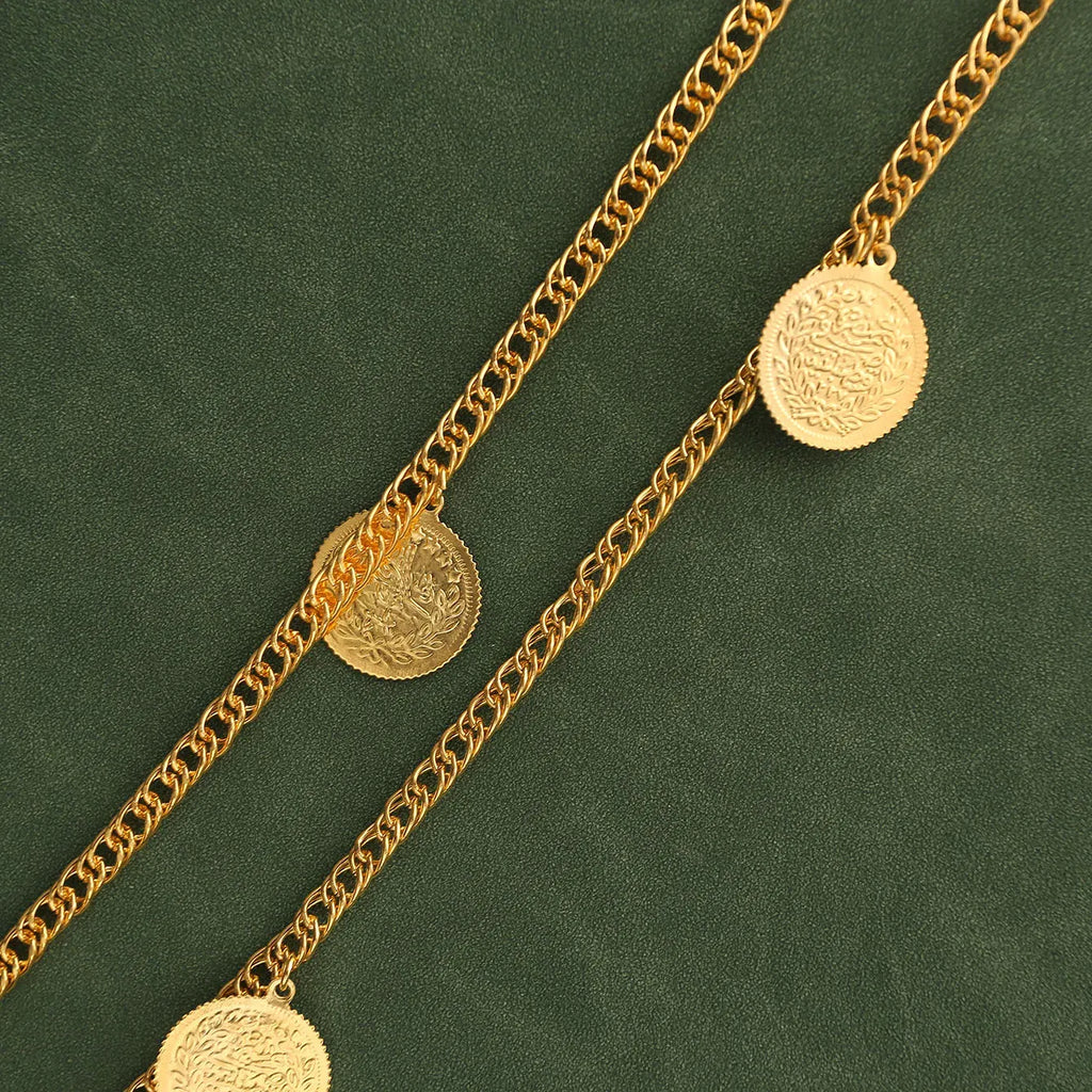 Gold chain necklace with coin pendants on a green background