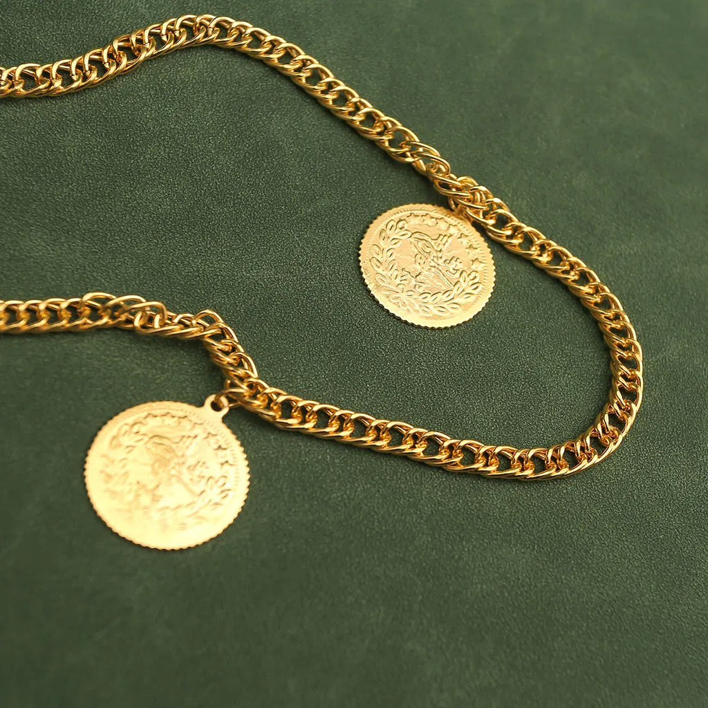 Gold chain necklace with two coins on a green background