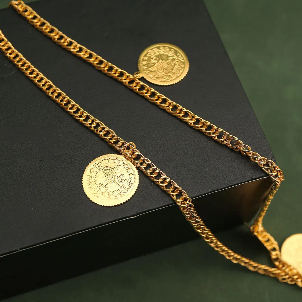 Gold chain and coins on a black surface with a green background